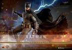 Action shot of Batman (2.0) hanging from a diorama backdrop of antiquated alleyways, holding a pistol in his left hand, looking to his left. (Prototype Shown) View 1