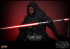 Half body shot of Darth Maul (Sith Speeder) (Special Edition) in a black hooded robe, holding a dual lightsaber horizontally in his left hand in front of his torso, with a serious expression. (Prototype Shown) View 13