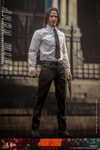 Lower right angle shot of John Wick® without a suit jacket, holding a wood-grain pistol with a menacing expression in front of a government building. (Prototype Shown) View 5
